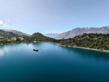 Spirit of Queenstown cruise boat floating on the calm, turquoise waters of Bob’s Cove, surrounded by lush greenery and majestic mountain views