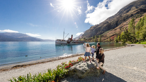 A family views the TSS Earnslaw departing from the Walter Peak shoreline