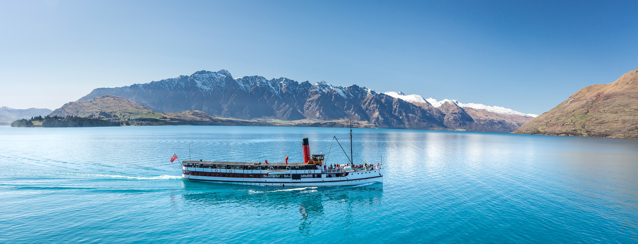 The TSS Earnslaw cruises across Lake Wakatipu with Remarkables in the background