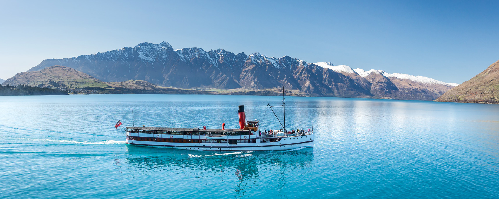 The TSS Earnslaw cruises across Lake Wakatipu with Remarkables in the background