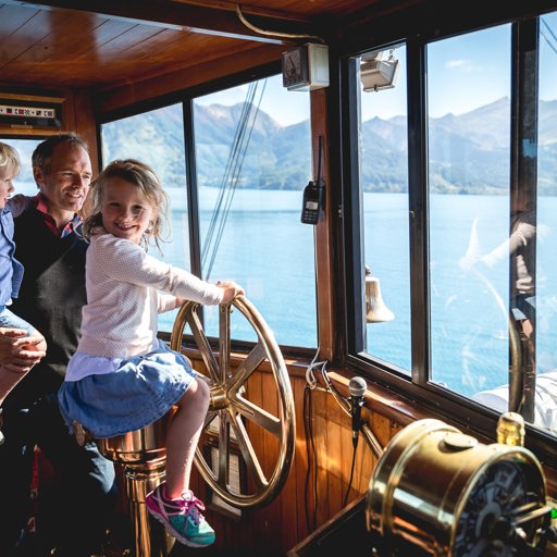 A young girl takes the wheel of the TSS Earnslaw steamship while cruising