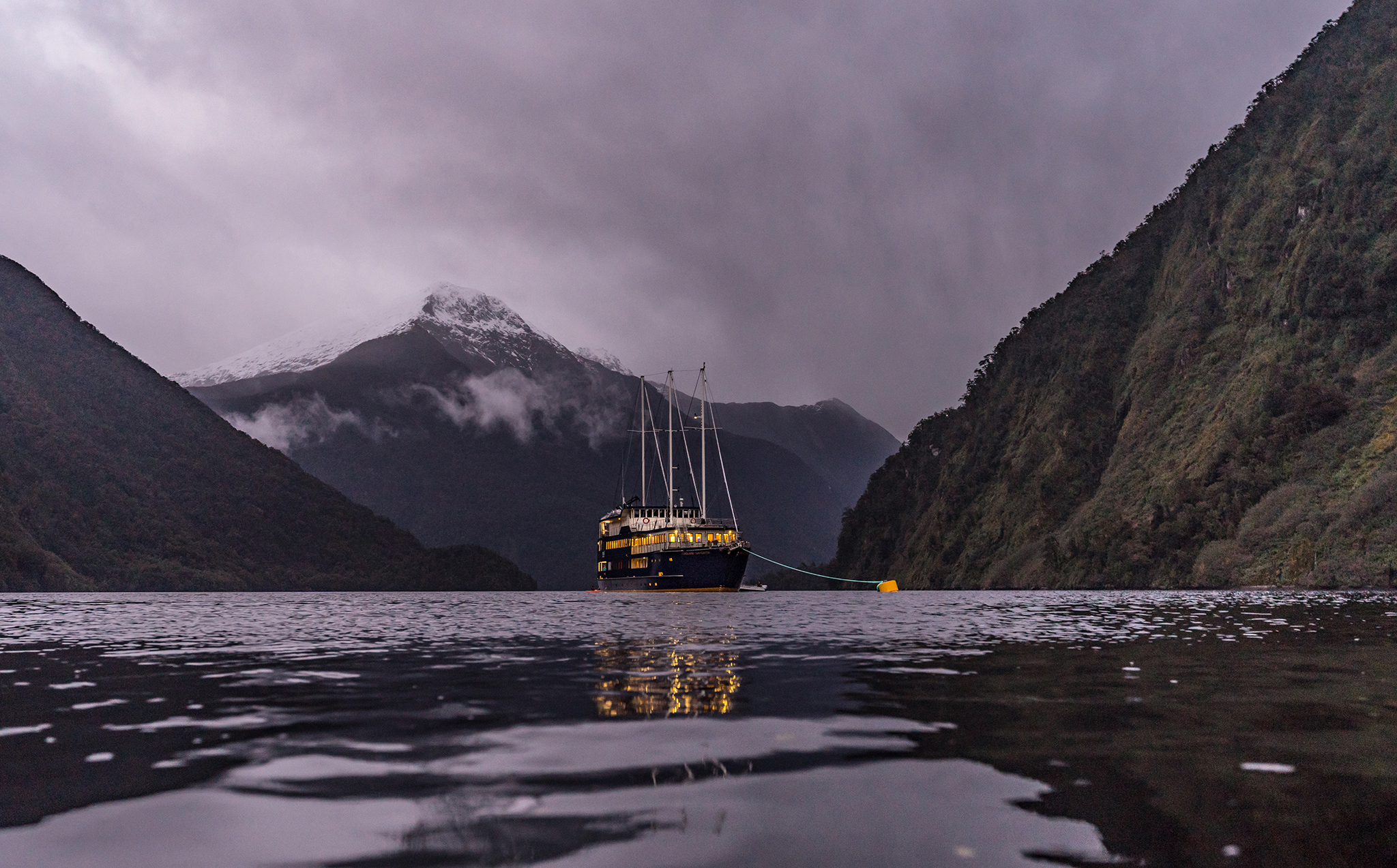 Boat docks of the night in Doubtful Sound with snow-capped mountain