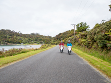 Two people on scooter on Stewart Island coastal road