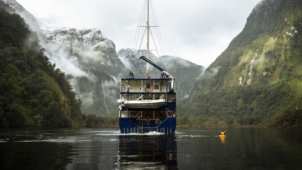 Kayaker on Doubtful Sound next to the Fiordland Navigator