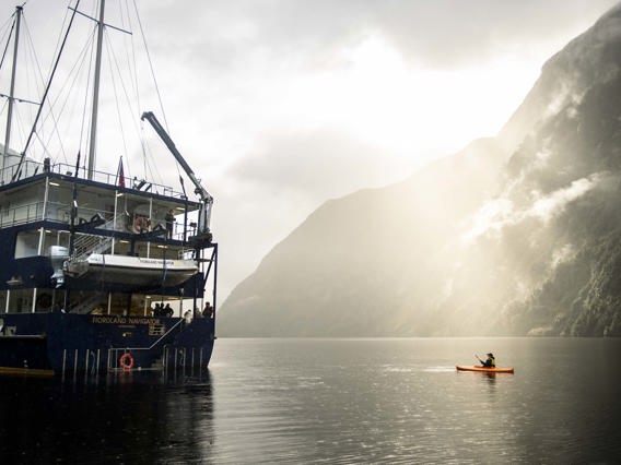 Kayaker on Doubtful Sound next to the Fiordland Navigator