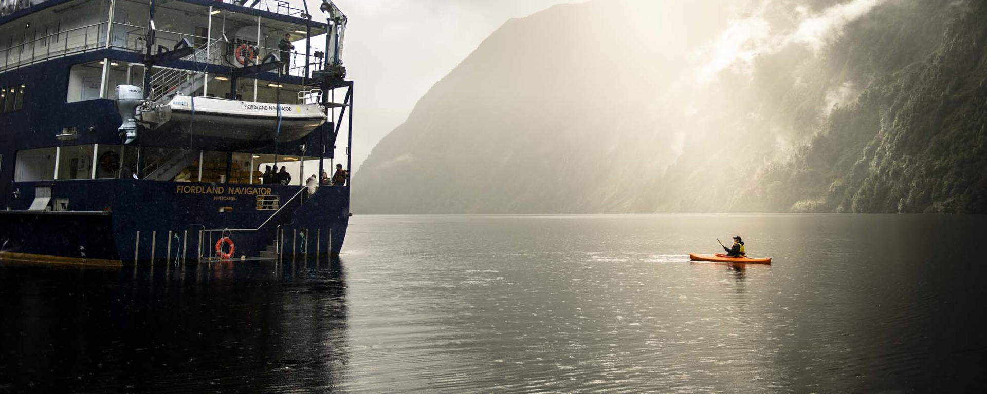 Kayaker on Doubtful Sound next to the Fiordland Navigator