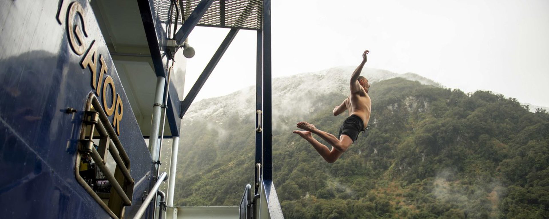 Man jumping off boat into Doubtful Sound waters