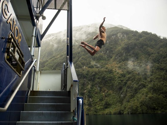 Man jumping off boat into Doubtful Sound waters