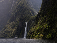 The Milford Mariner vessel cruises close to a cascading waterfall in Milford Sound