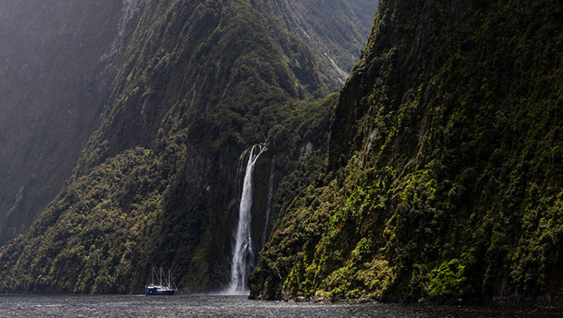 The Milford Mariner vessel cruises close to a cascading waterfall in Milford Sound