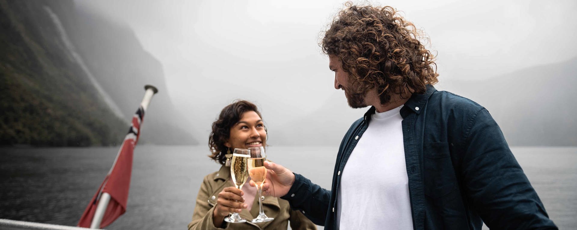 A couple cheers a glass of champaign on board the premium cruise in Milford Sound