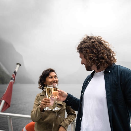 A couple cheers a glass of champaign on board the premium cruise in Milford Sound