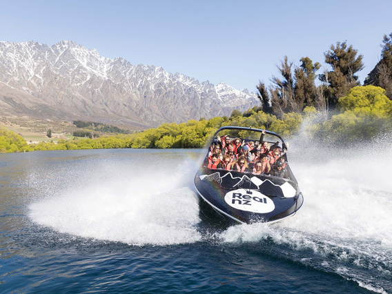 An excited crowd enjoy a 360 spin in the Queenstown Jet Boat in front of the Remarkables mountain range