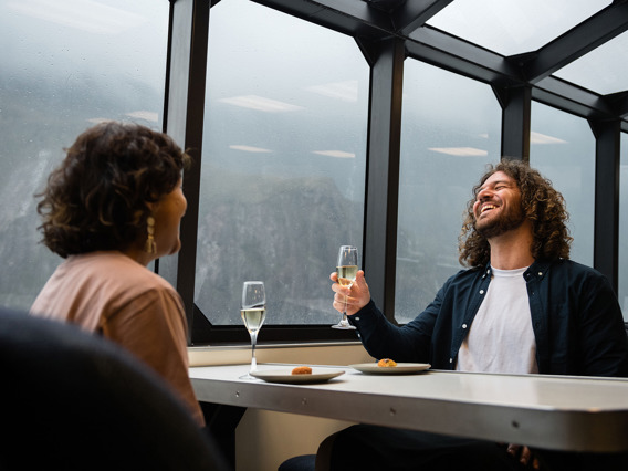 A couple enjoy a glass of champaign onboard a luxury boat on Milford Sound