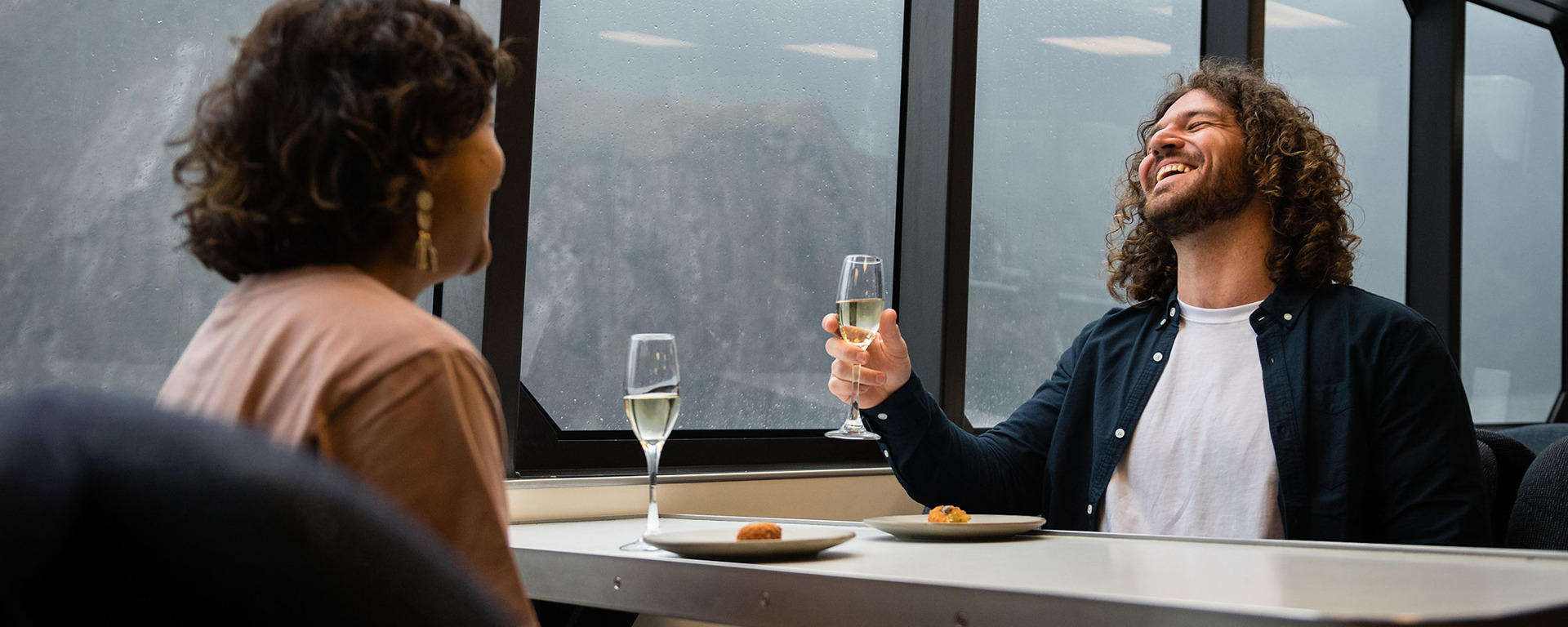 A couple enjoy a glass of champaign onboard a luxury boat on Milford Sound