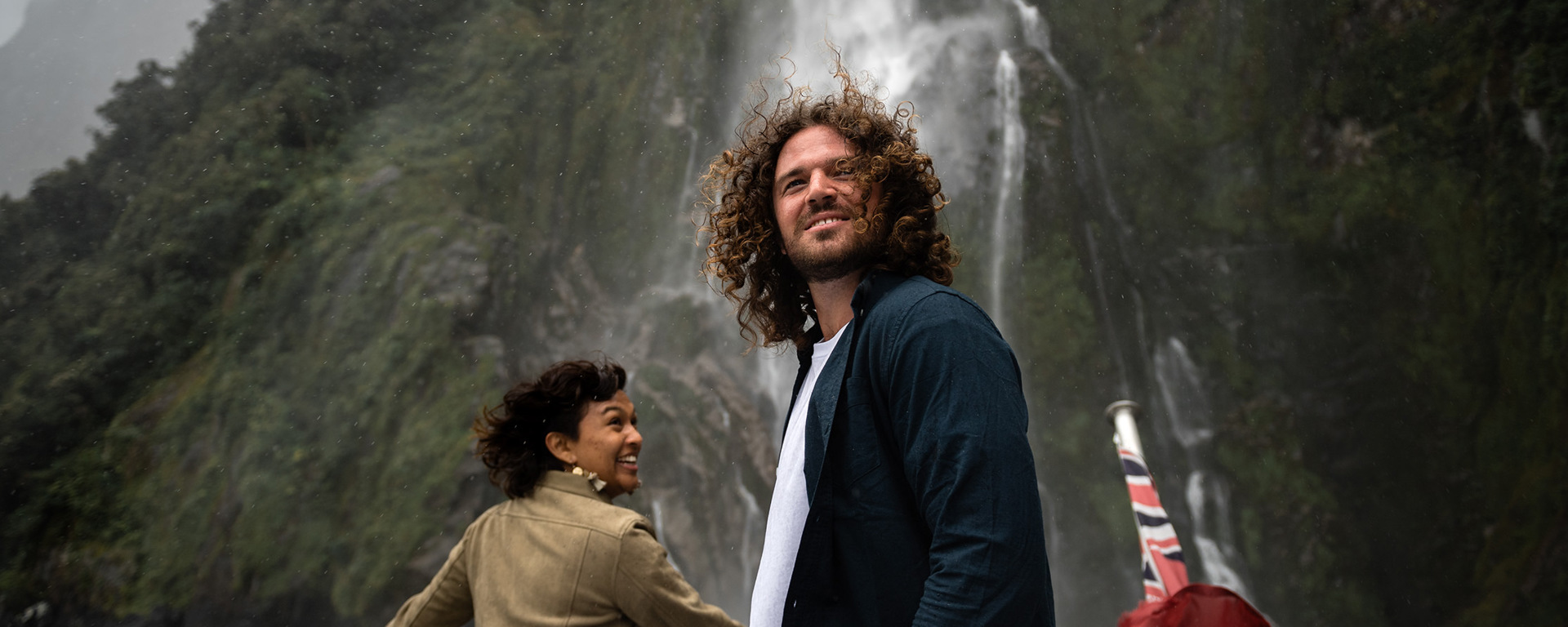 A couple enjoy being up close to a waterfall while cruising n Milford Sound