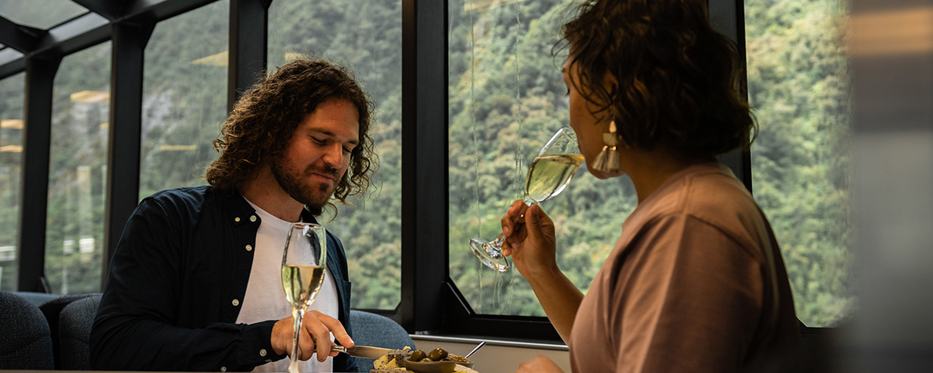 A couple enjoy a cheese board while cruising in Milford Sound on a premium experience 