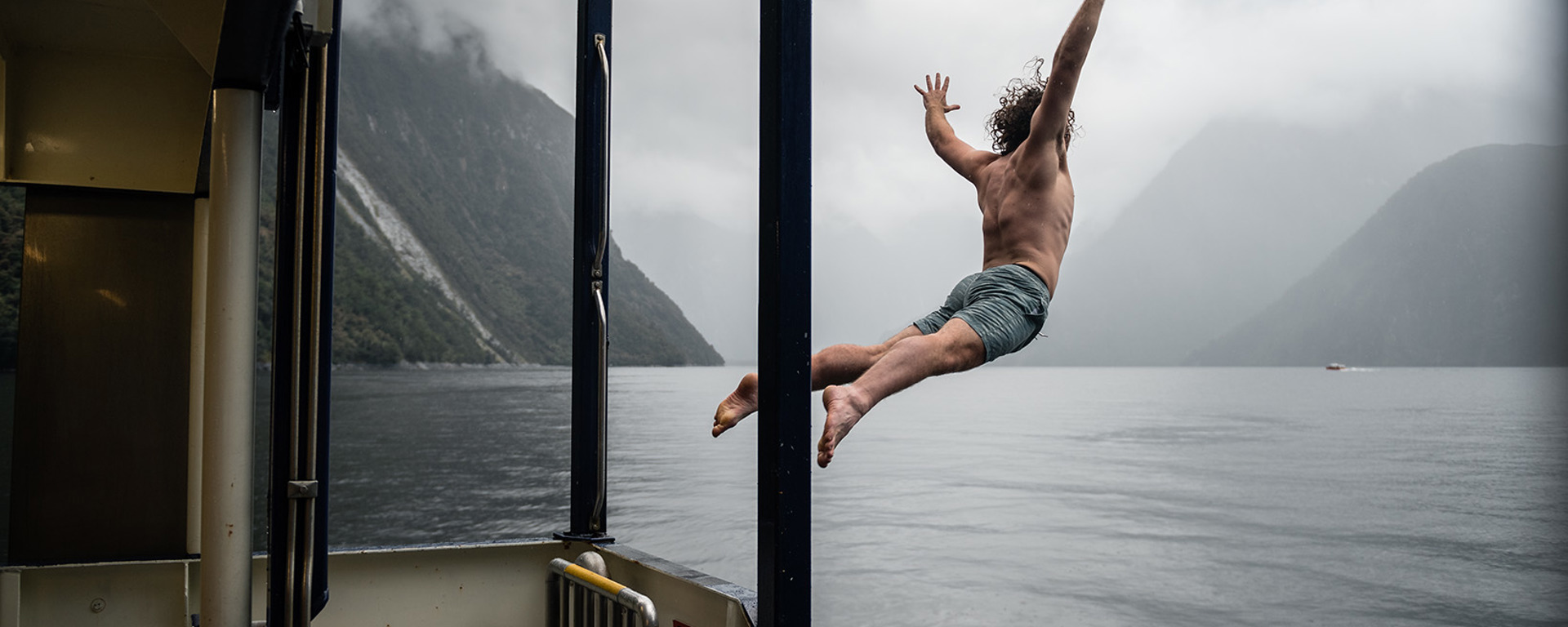 A man jumps from the Milford Wanderer into the moody water