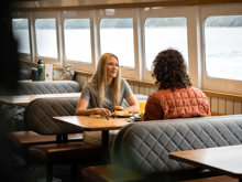 A couple enjoys a seat in the inside cabin of a RealNZ cruise vessel in Milford Sound.