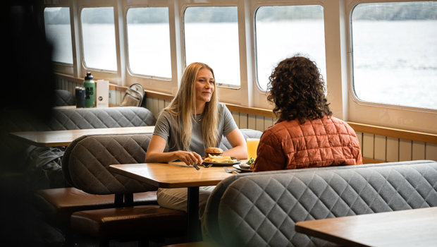 A couple enjoys a seat in the inside cabin of a RealNZ cruise vessel in Milford Sound.