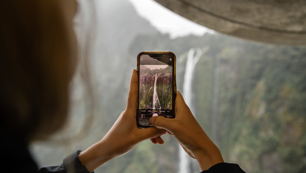 A person captures an image of a Milford Sound waterfall on their iPhone