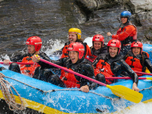 A group of rafters getting splashed with white water on the shotover river