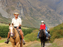 A dog leads a group on a horse trek through Walter Peak farm 