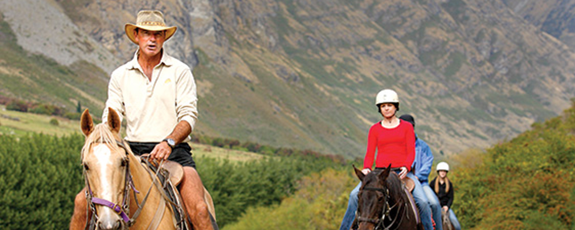 A dog leads a group on a horse trek through Walter Peak farm 