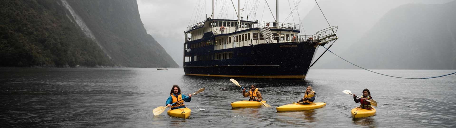 Four kayakers in front of overnight boat