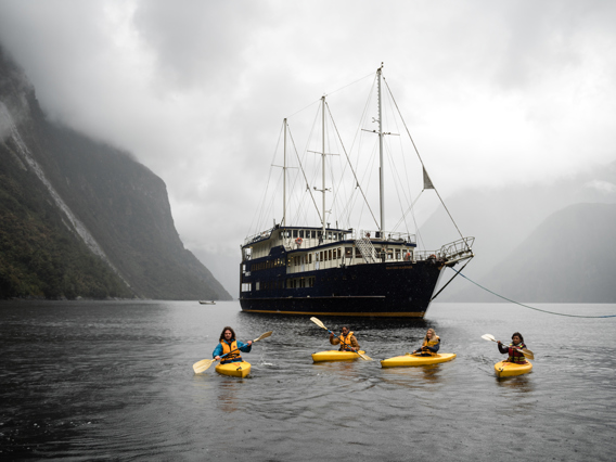 Four kayakers in front of overnight boat