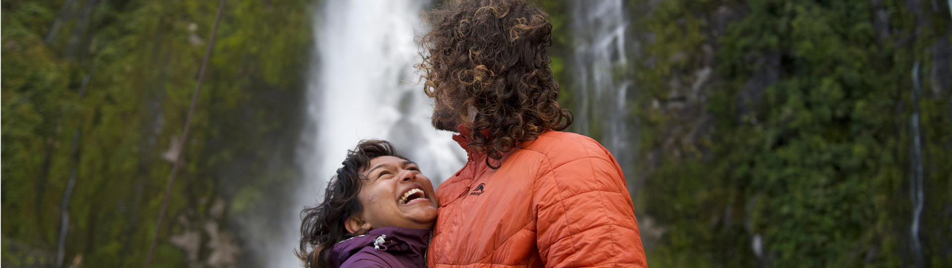 A couple hugging in front of a waterfall