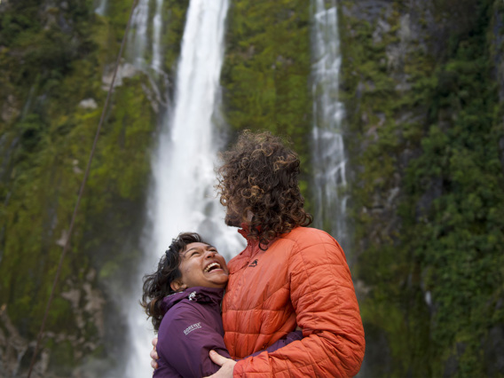 A couple hugging in front of a waterfall