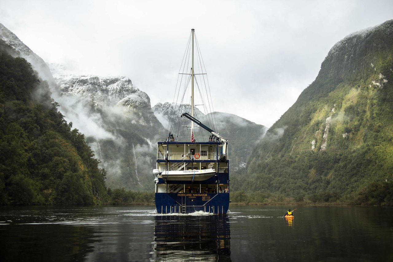 A close shot of the Fiordland Navigator docked in Doubtful Sound, alongside a man kayaking