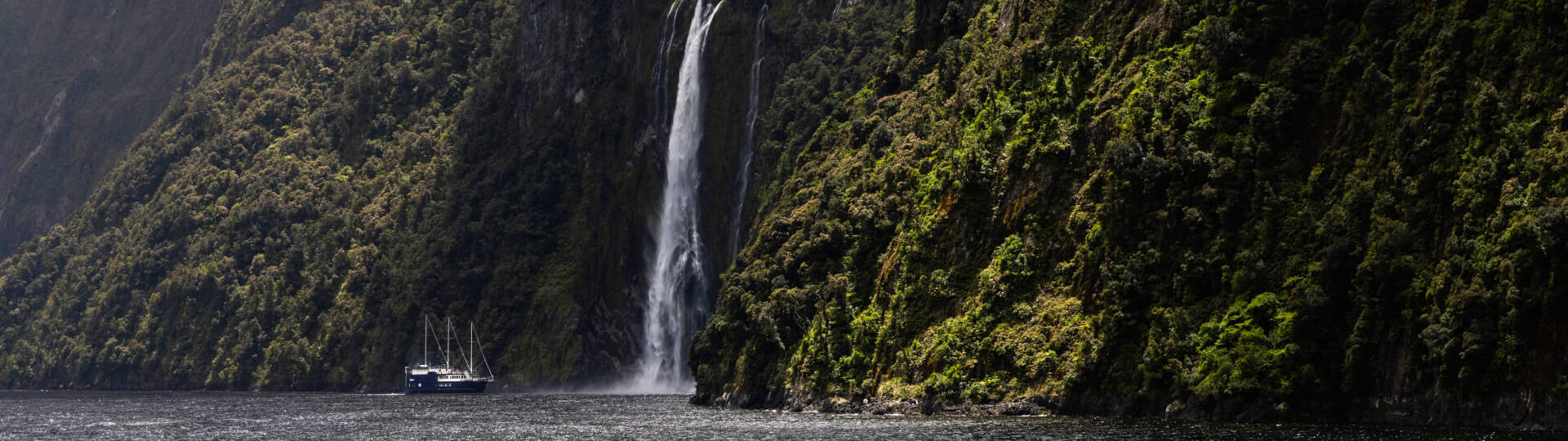 A large sailboat approaches the famous Stirling Falls in Milford Sound, NZ.