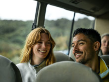 A couple smiling on village and bays coach