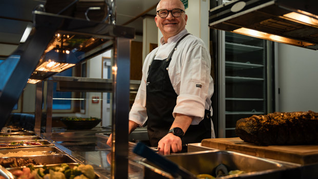 A chef stands ready to serve food to customers onboard a Doubtful Sound Overnight Cruise experience.