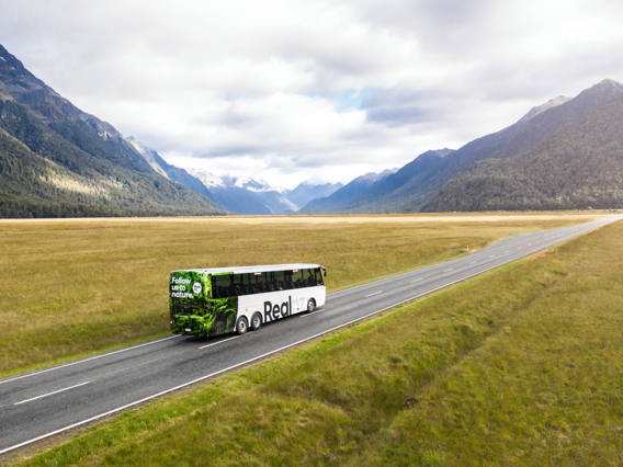 A bus drives through the Eglinton Valley on its way to Milford Sound.