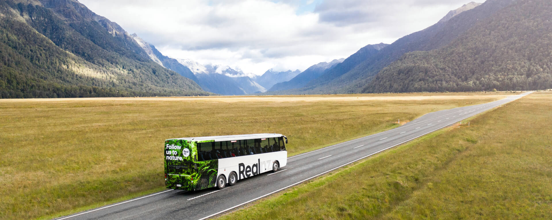 A bus drives through the Eglinton Valley on its way to Milford Sound.