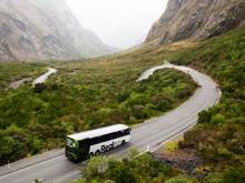 A bus drives down a scenic and windy section of road on the last approach to Milford Sound.