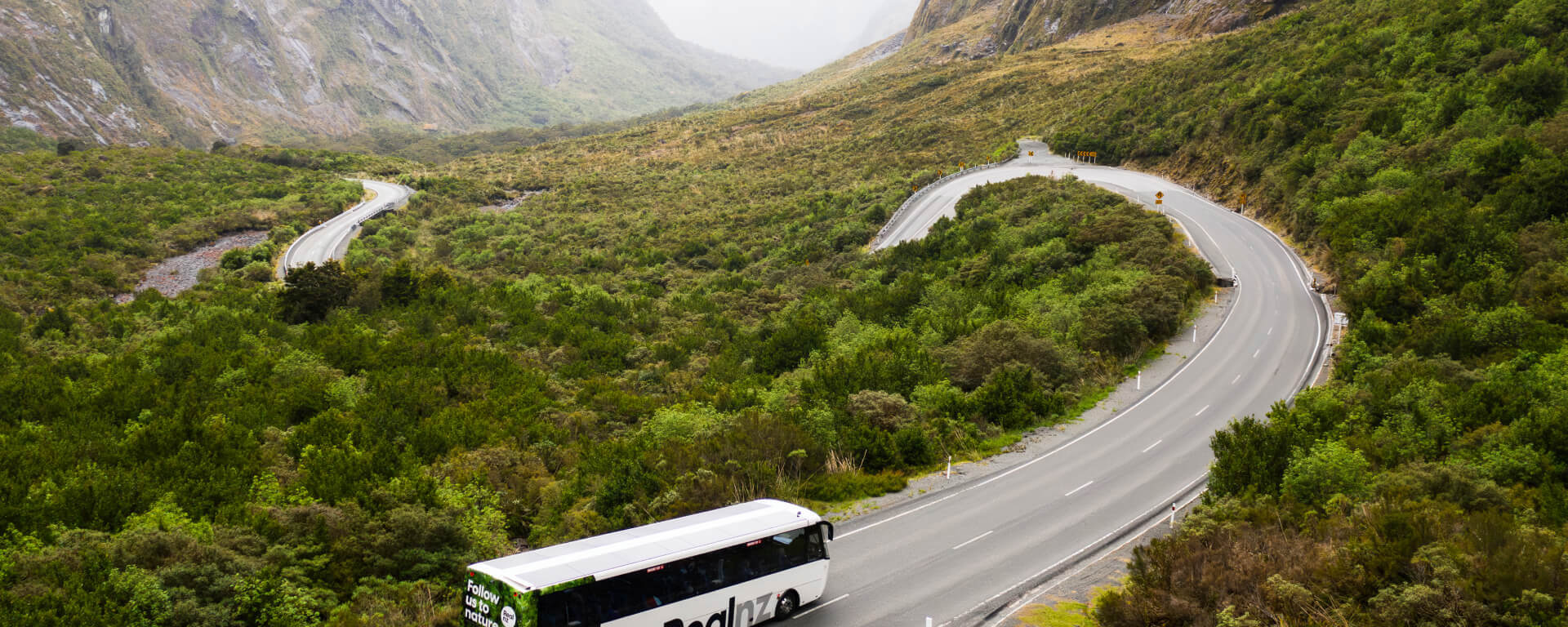 A bus drives down a scenic and windy section of road on the last approach to Milford Sound.