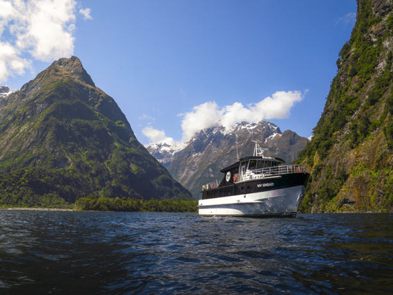 The Sinbad cruise vessel with towering mountains in Milford Sound