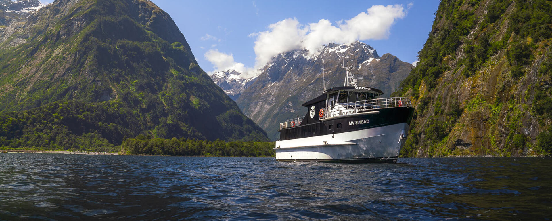 The Sinbad cruise vessel with towering mountains in Milford Sound